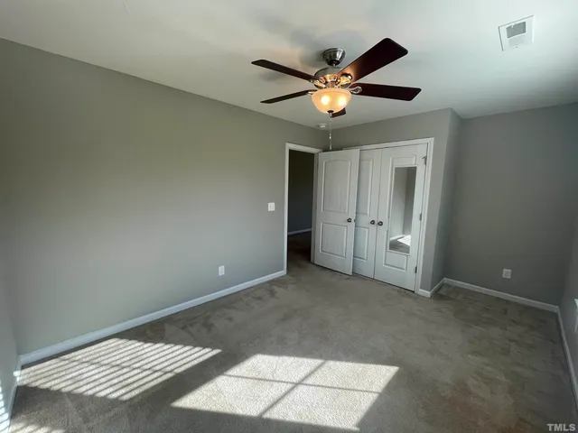 an empty room with closet and a chandelier fan
