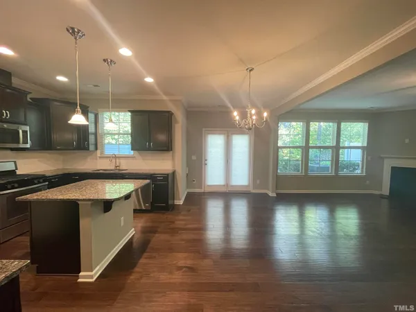 a large kitchen with kitchen island a stove a sink a large island with wooden floor and cabinets