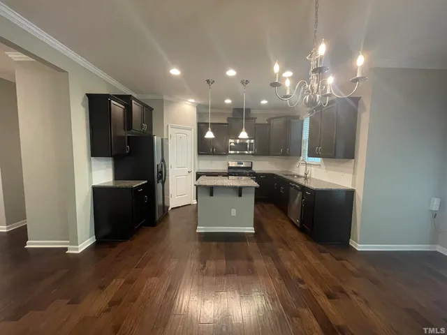 a large kitchen with a center island wooden floor stainless steel appliances and a window