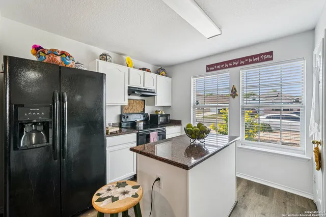 a kitchen with granite countertop a refrigerator and a window