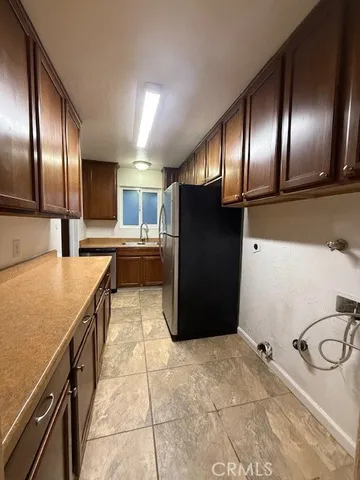 a kitchen with granite countertop stainless steel appliances a refrigerator stove top oven and sink
