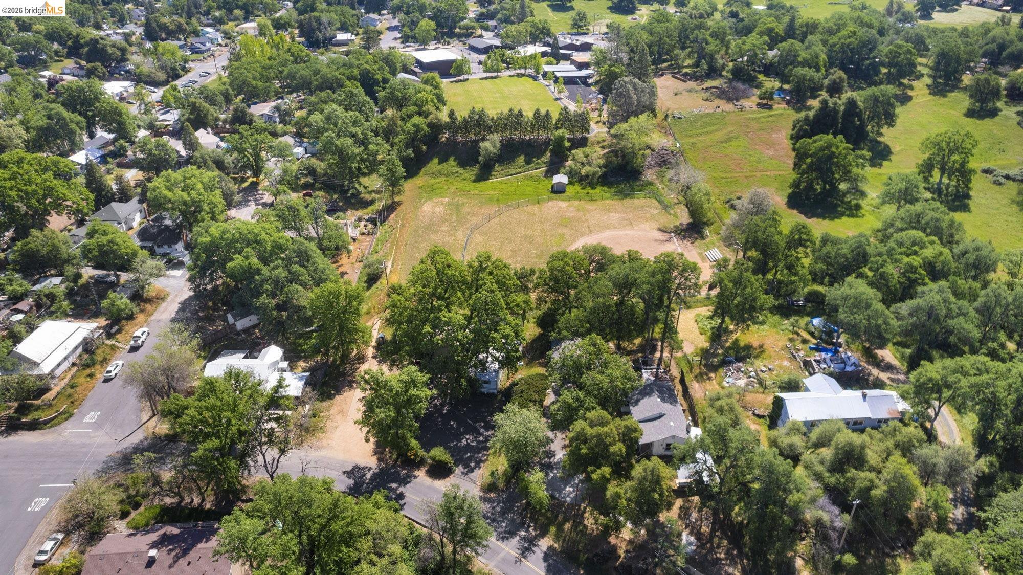 18363 Yosemite Road Tuolumne, CA 95379 - Photo 32 of 34 Expansive parcel featuring mature trees, a cleared open field, and surrounding residential properties