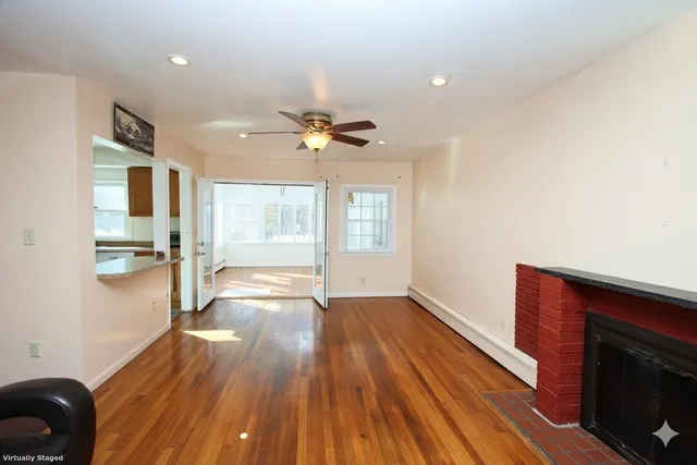 a view of empty room with wooden floor and fan