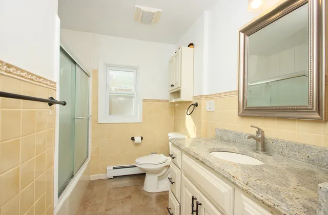 a bathroom with a granite countertop sink toilet and shower