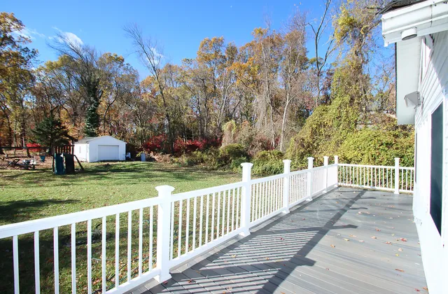 a view of a white house with a yard and trees