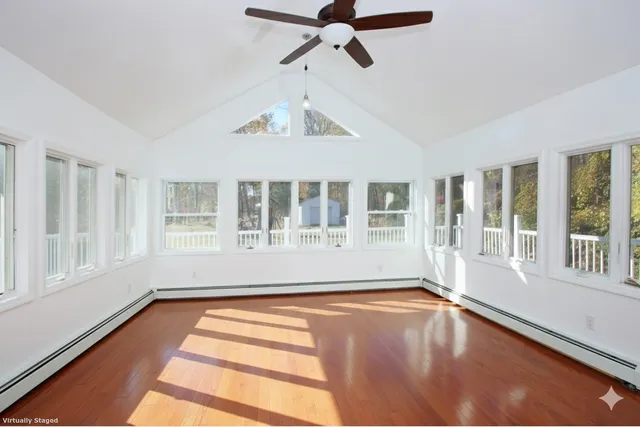 a view of an empty room with a window and wooden floor