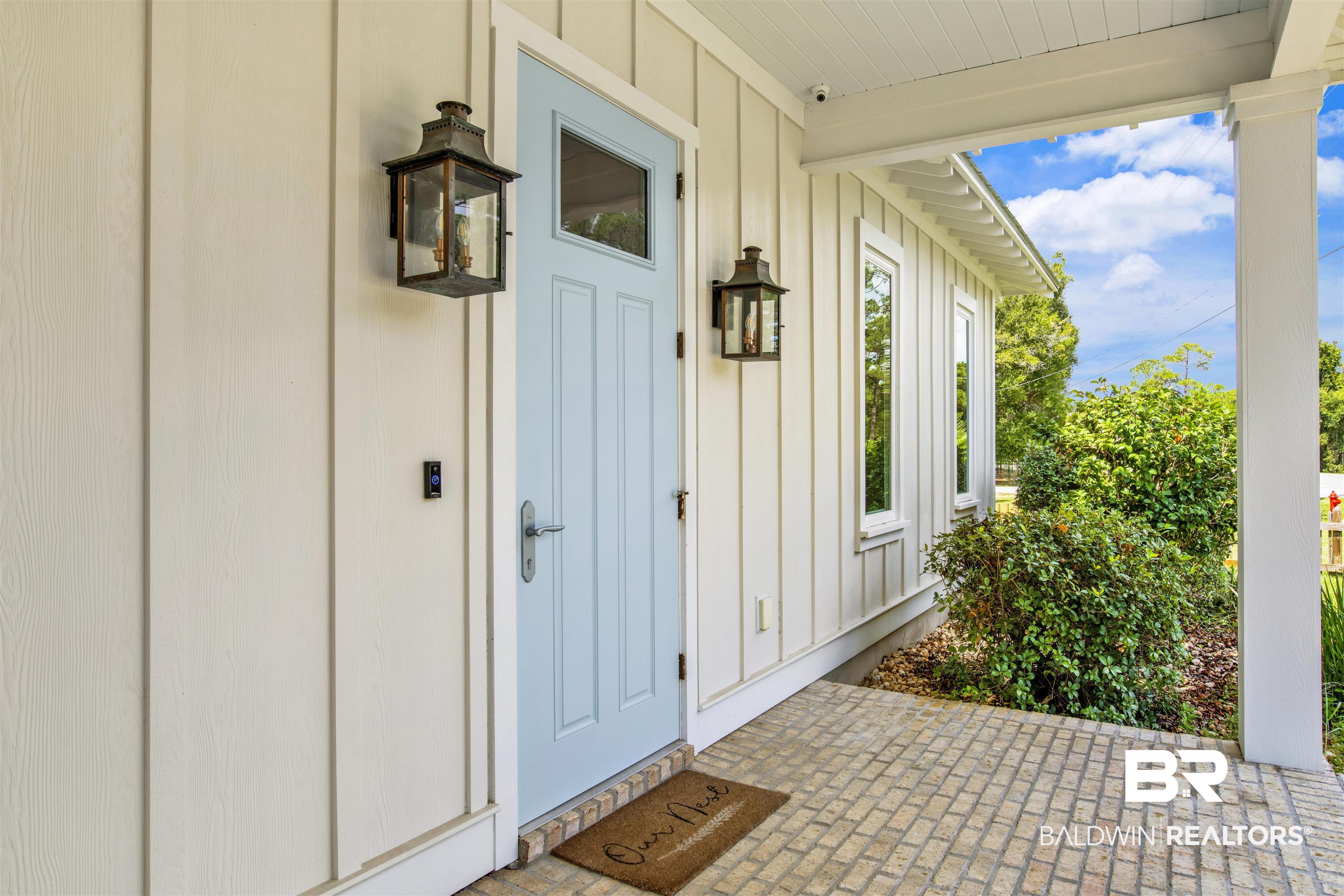 27980 Canal Road Orange Beach, AL 36561 - Photo 17 of 46 View of exterior entry featuring board and batten siding and covered porch