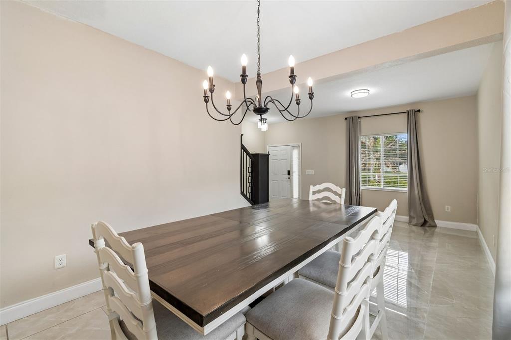 2829 Pankaw Lane Valrico, FL 33596 - Photo 10 of 55 a dining room with wooden floor a chandelier a wooden table and chairs