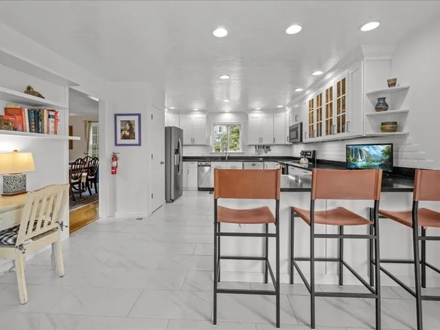a dining area with stainless steel appliances kitchen island granite countertop a table and chairs