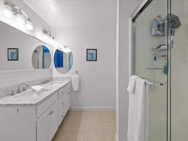 a bathroom with a double vanity sink mirror and shower