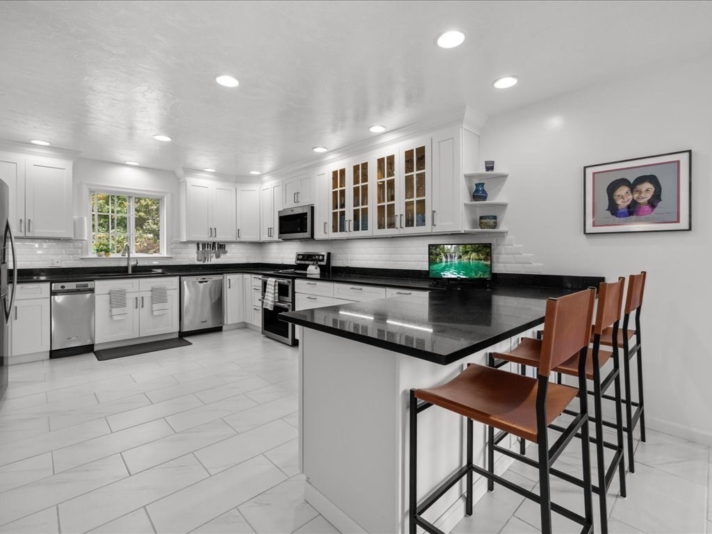 6 Wood Street Upton, MA 01568 - Photo 9 of 40 a kitchen with stainless steel appliances granite countertop a stove top oven a sink a dining table and chairs