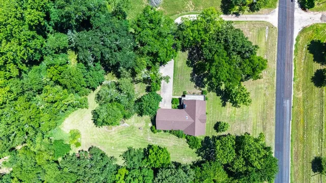 an aerial view of residential house with outdoor space and trees all around