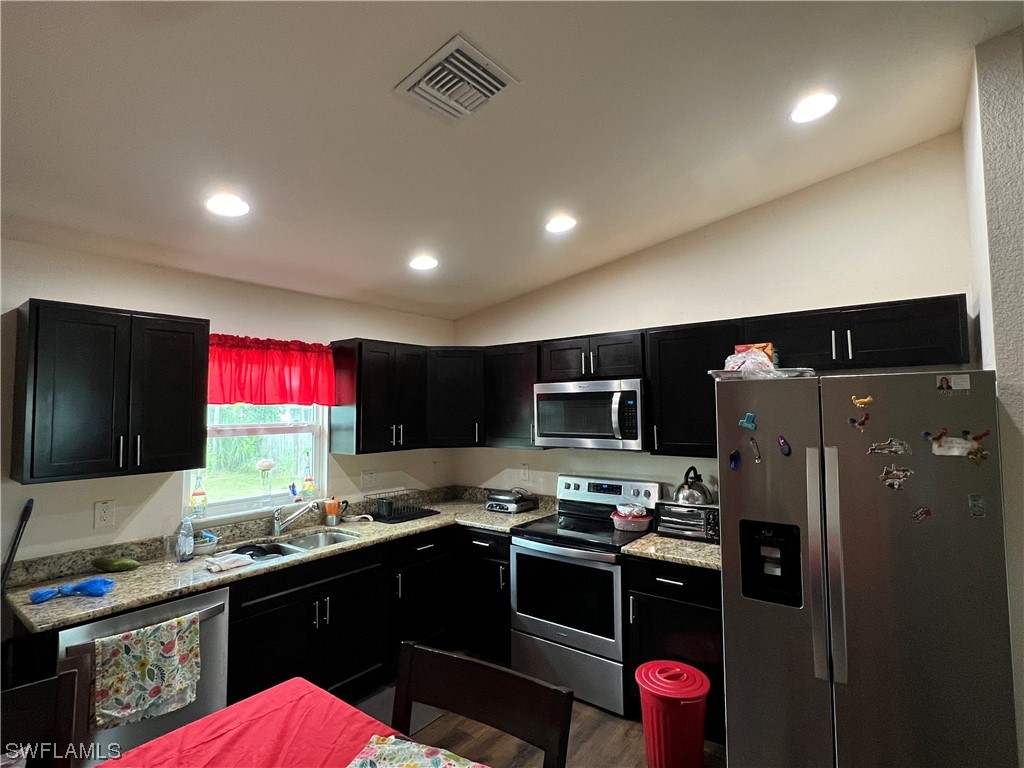 5018 Dolphin Circle LaBelle, FL 33935 - Photo 5 of 17 a kitchen with stainless steel appliances kitchen island granite countertop a refrigerator stove and sink