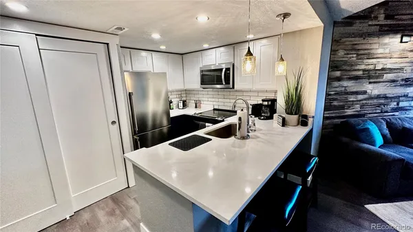 a kitchen with stainless steel appliances a refrigerator a stove a sink a dining table and chairs