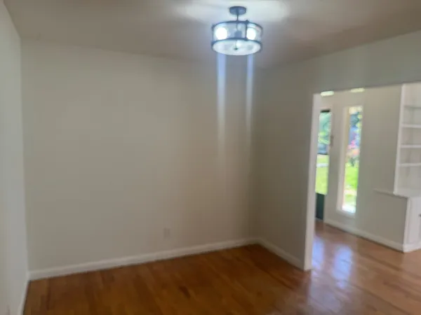 a view of an empty room with wooden floor and a chandelier
