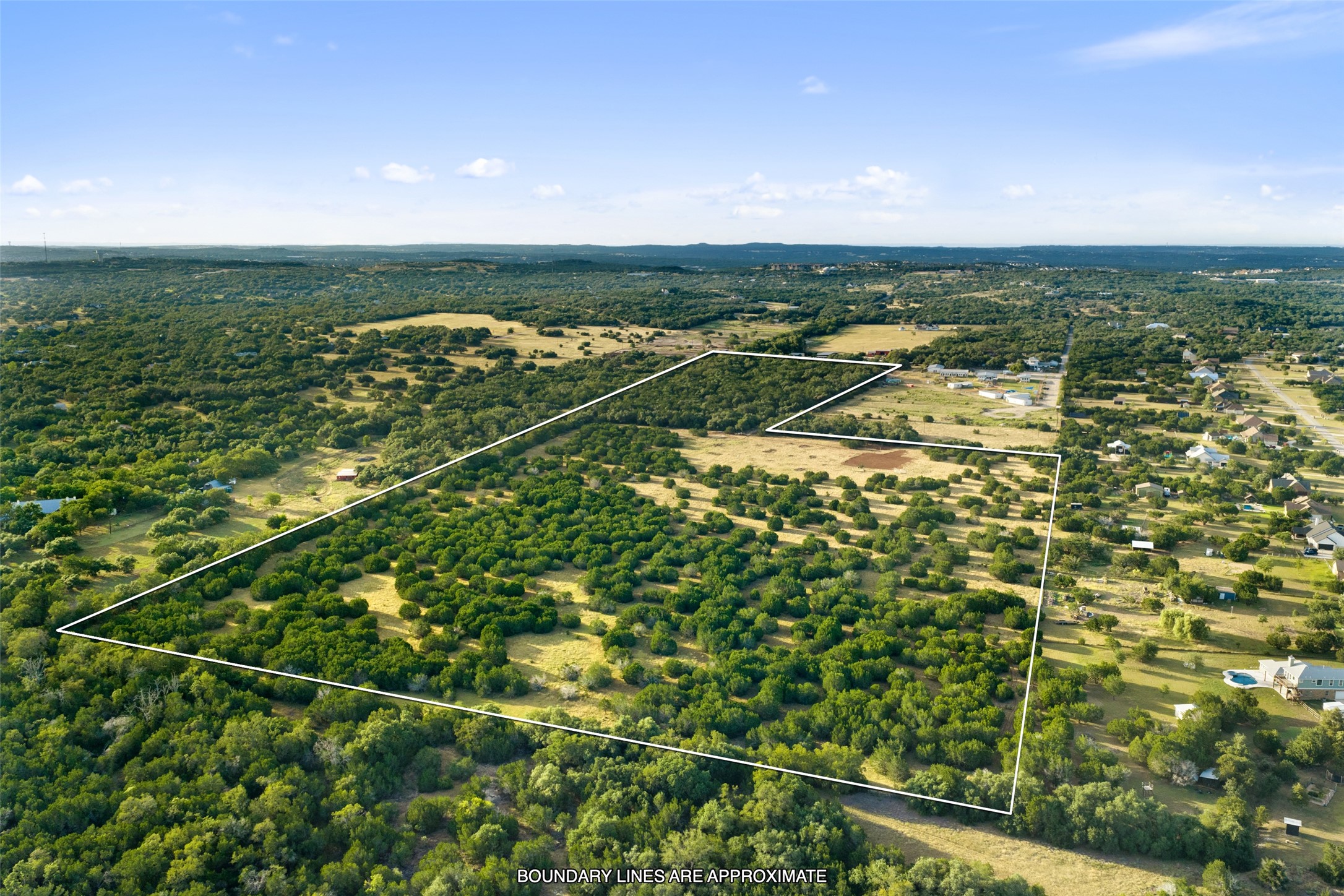 0 Hays Country Acres Road Dripping Springs, TX 78620 - Photo 14 of 33 Mature trees scatter across a vast countryside acreage framed by rolling green hills.