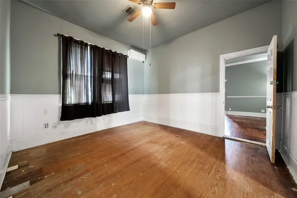 an empty room with wooden floor cabinet and a ceiling fan