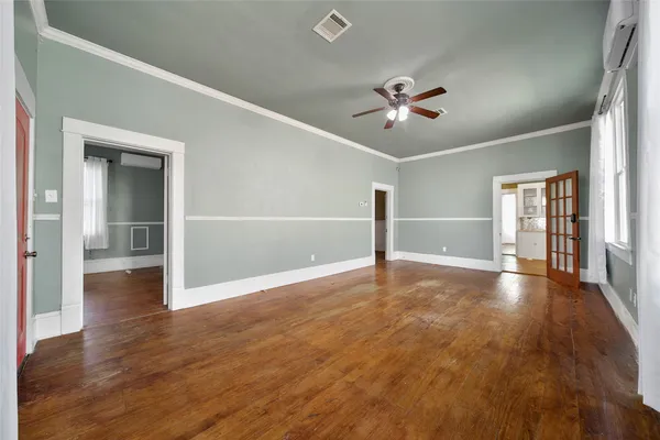 an empty room with wooden floor and chandelier fan