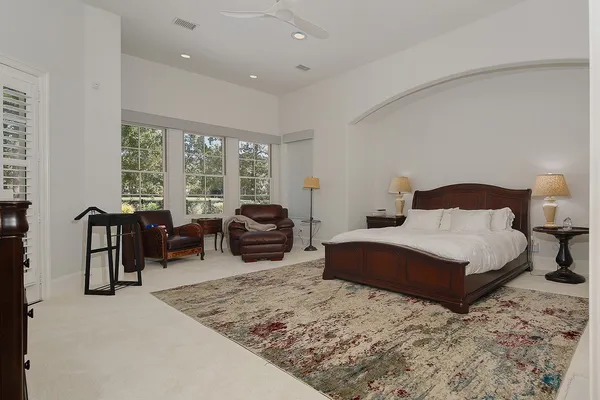 a spacious bedroom with a bed a table chair and a large window