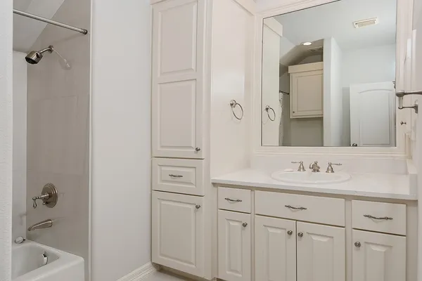 a bathroom with a bathtub sink vanity granite and shower