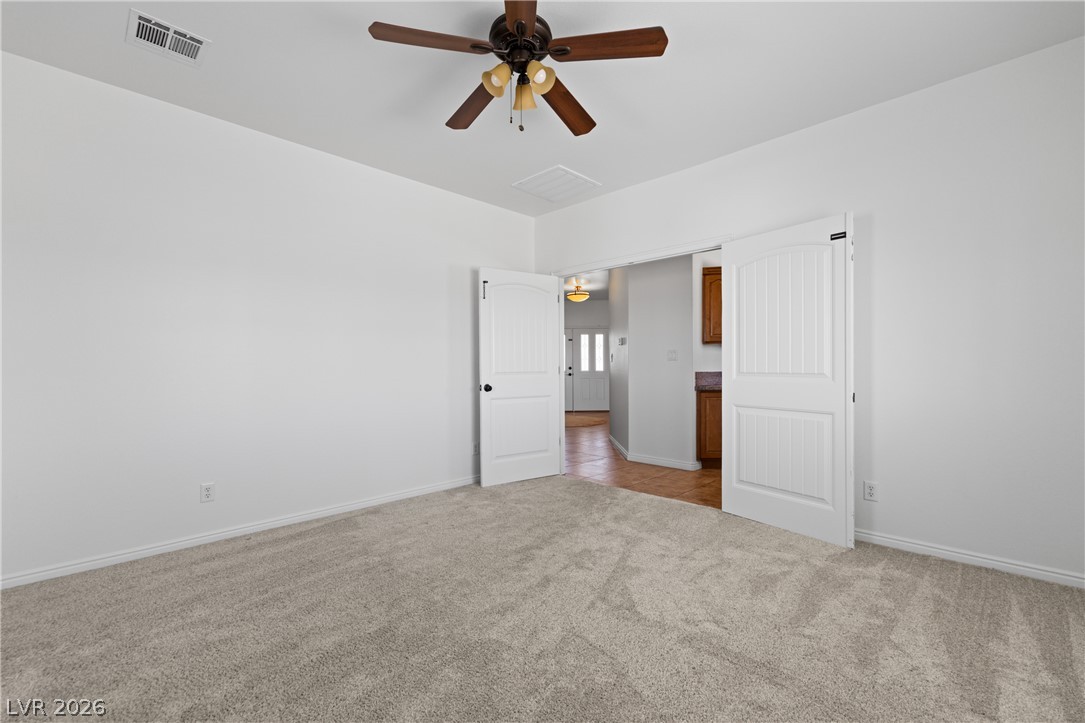 575 Gann Avenue Logandale, NV 89021 - Photo 24 of 75 Well-lit and versatile room offers comfortable carpeted flooring and a classic ceiling fan.