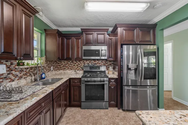 a kitchen with stainless steel appliances granite countertop a refrigerator stove and sink