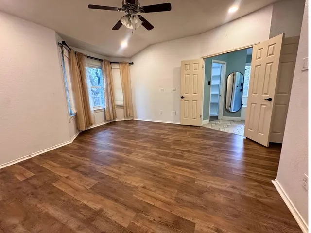 a view of an empty room with window and wooden floor