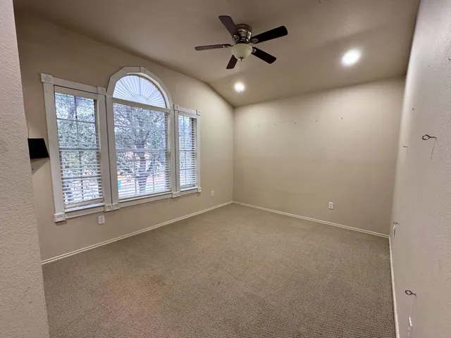 en empty room with windows and ceiling fan