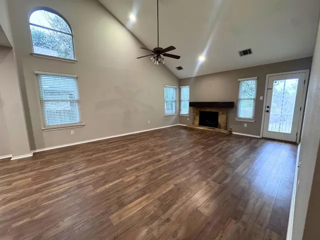 an empty room with windows fireplace and wooden floor