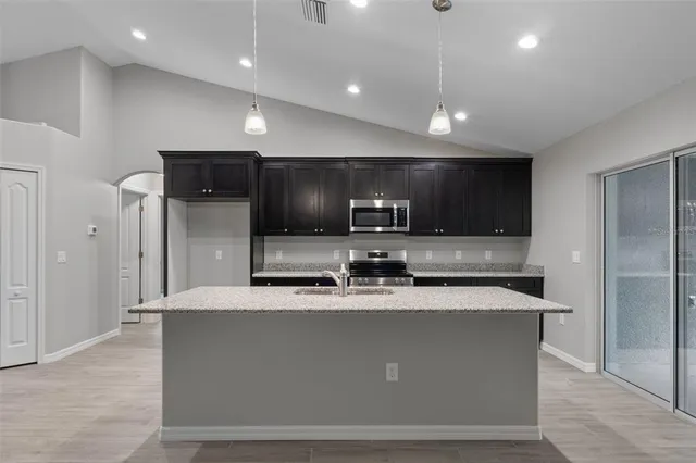 a large kitchen with kitchen island a sink stainless steel appliances and cabinets