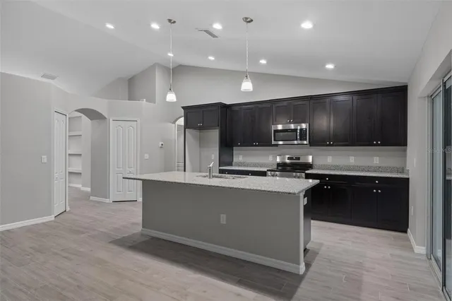 a kitchen with kitchen island granite countertop wooden cabinets and stainless steel appliances