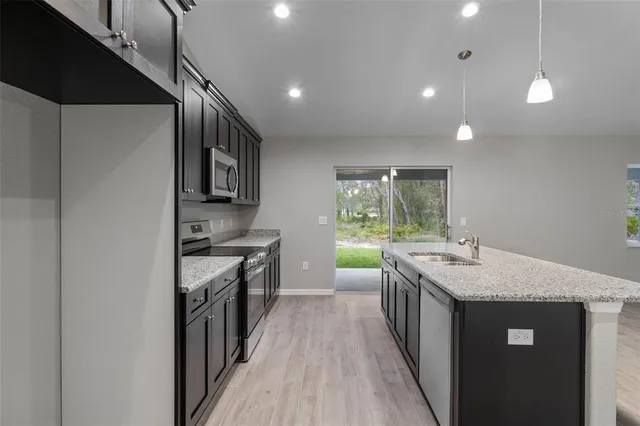 a kitchen with kitchen island granite countertop a sink stove and refrigerator