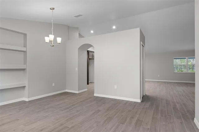 an empty room with wooden floor and chandelier