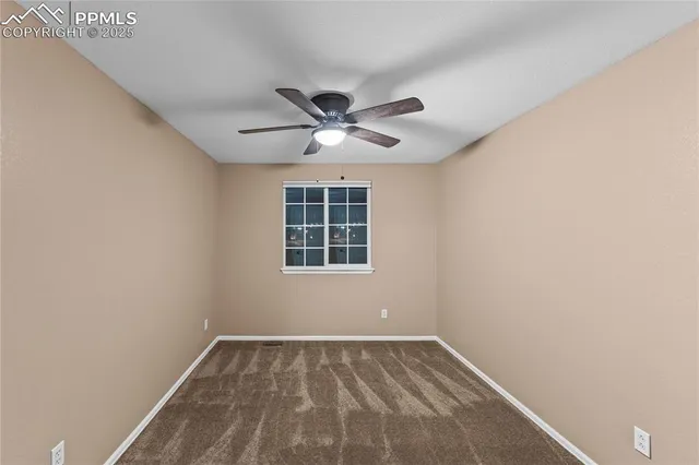 an empty room with a window and a fan