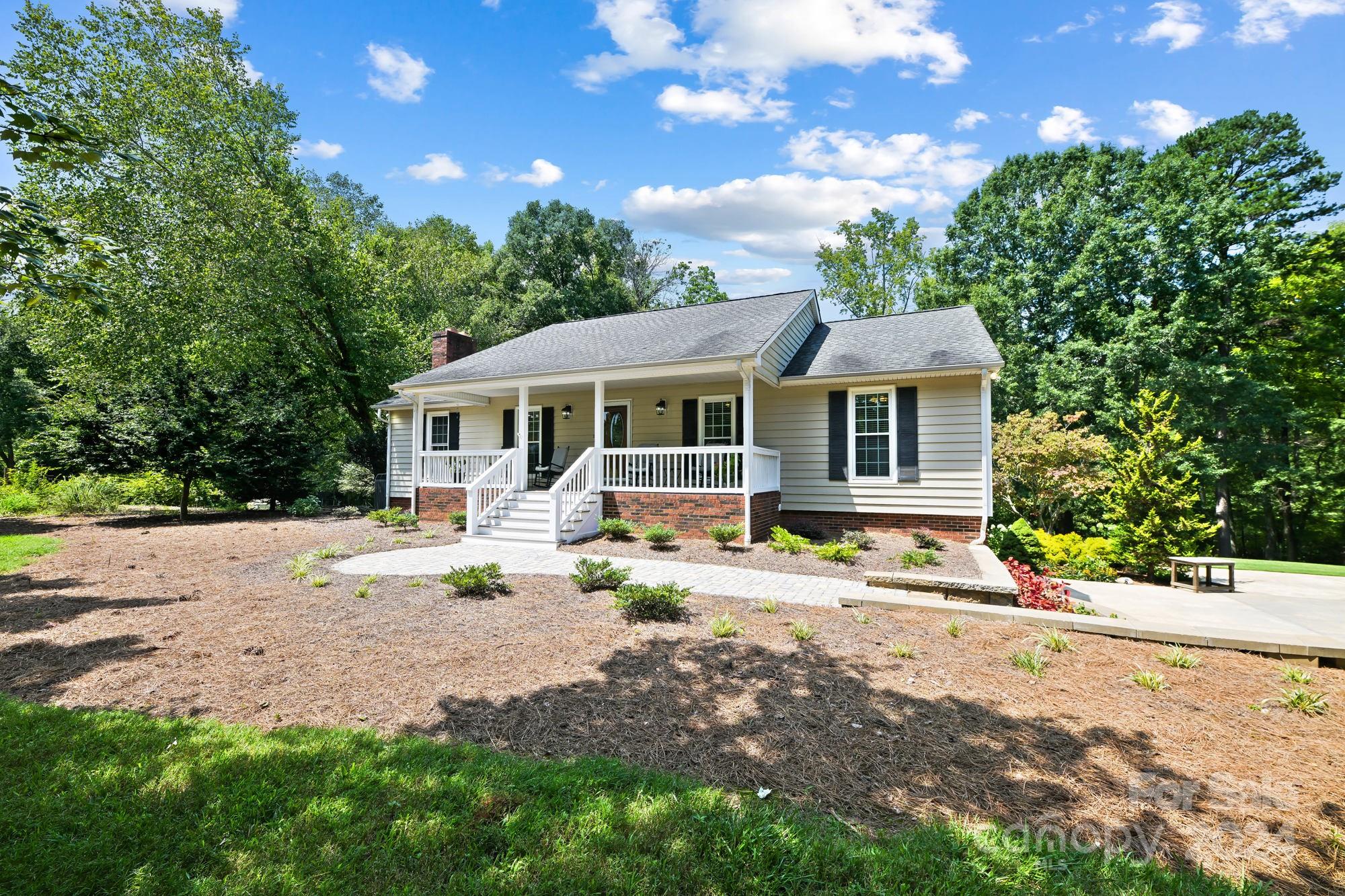 1135 Arabian Farm Road Clover, SC 29710 - Photo 2 of 48 a view of a white house with large windows plants and a large tree