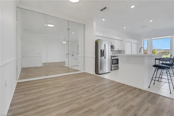 a view of kitchen with stainless steel appliances refrigerator wooden floor and cabinets