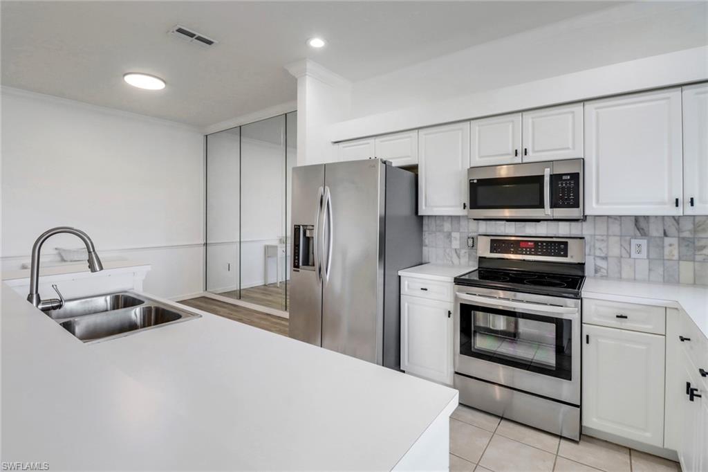 1677 Morning Sun Lane Naples, FL 34119 - Photo 8 of 41 a kitchen with stainless steel appliances a stove a sink and a refrigerator