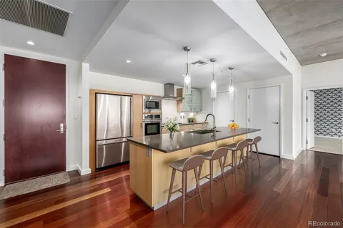 an open kitchen with wooden floor and stainless steel appliances