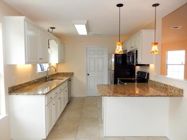 9 Stowe Road Mary Esther, FL 32569 - Photo 6 of 24 a kitchen with kitchen island granite countertop a sink a counter top space appliances and cabinets