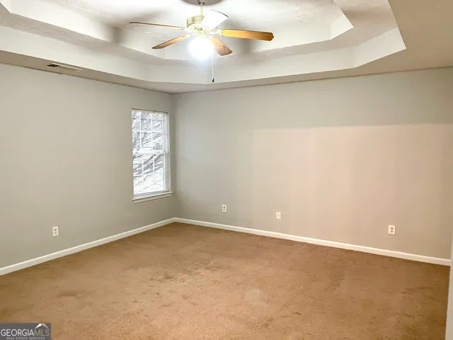 an empty room with windows and fan