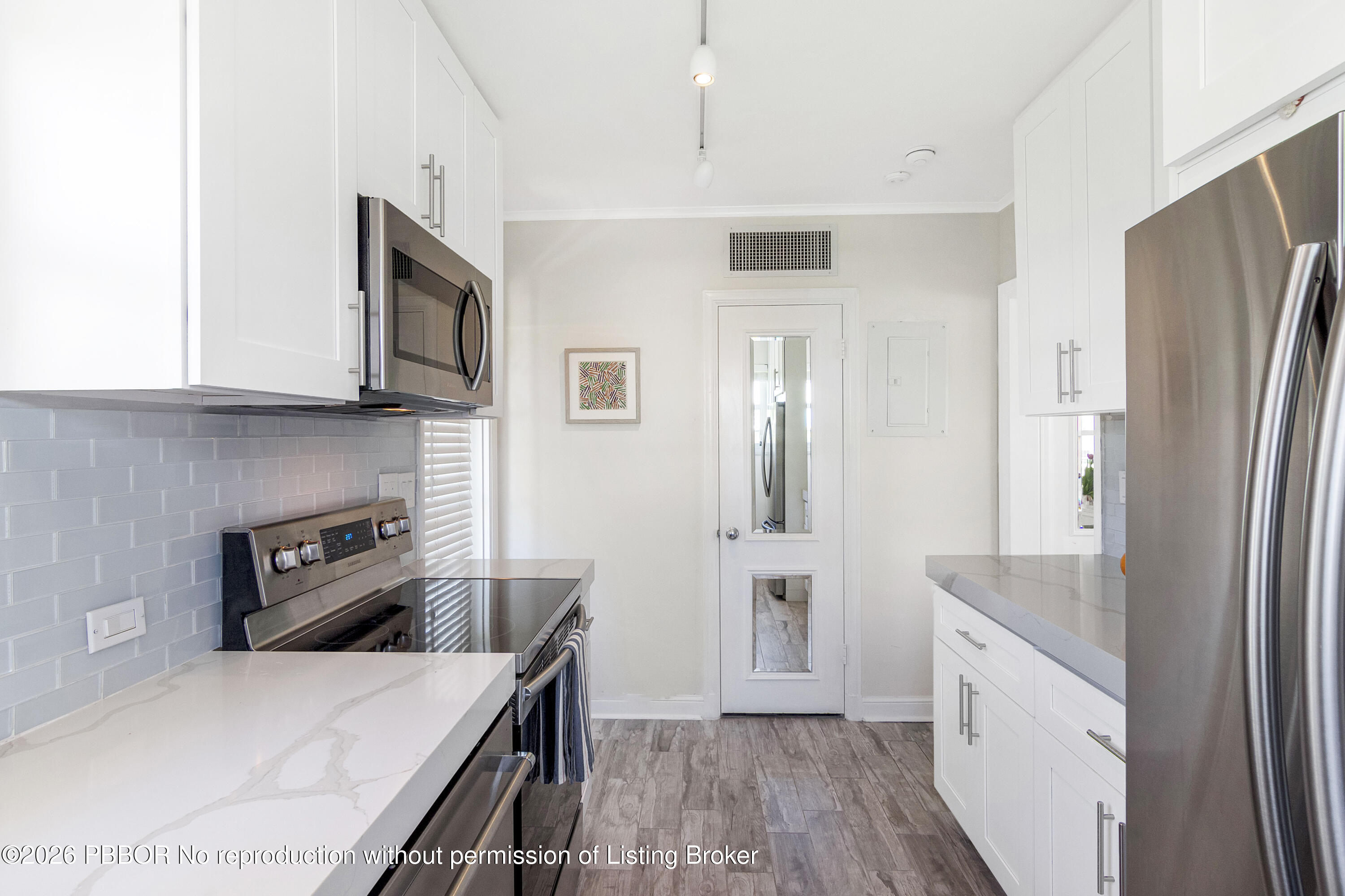 311 Cocoanut Row, Unit 201 Palm Beach, FL 33480 - Photo 11 of 12 a kitchen with stainless steel appliances granite countertop a refrigerator a stove and a sink with wooden floor