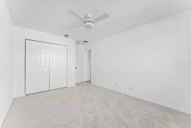an empty room with a ceiling fan and a window