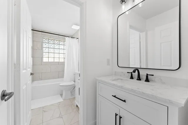 a bathroom with a double vanity sink toilet mirror and shower