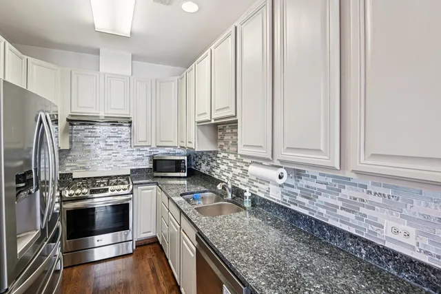 a kitchen with granite countertop a sink stainless steel appliances and cabinets