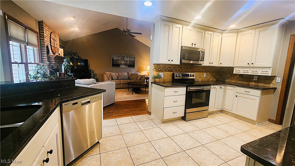 8329 Seasons Road Streetsboro, OH 44241 - Photo 7 of 35 Kitchen with lofted ceiling, decorative backsplash, appliances with stainless steel finishes, ceiling fan, and light hardwood / wood-style floors