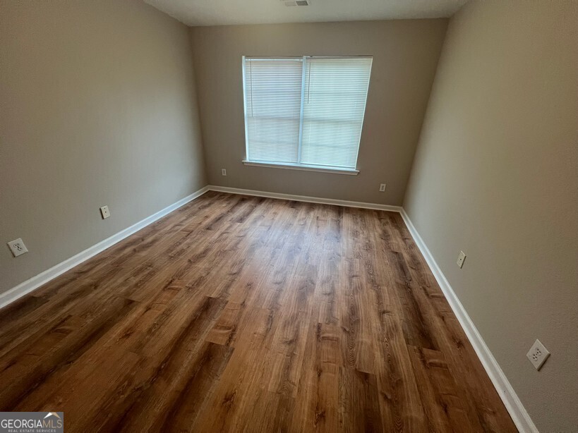 95 Creek Way Covington, GA 30016 - Photo 18 of 25 an empty room with wooden floor and windows