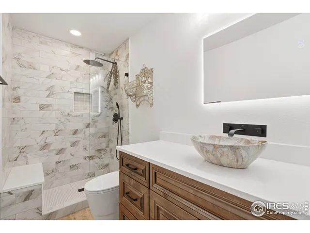 a bathroom with a granite countertop sink a toilet a mirror and shower