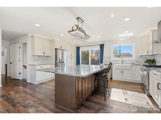 a kitchen with stainless steel appliances granite countertop a sink a stove a refrigerator cabinets and living room view