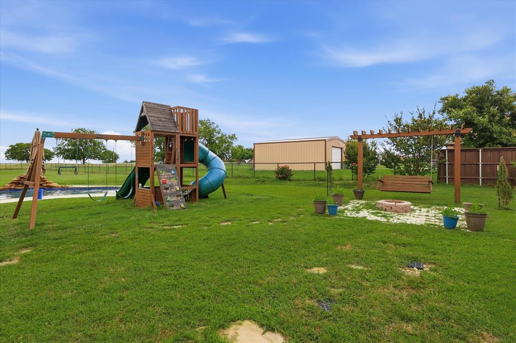 430 Ridgecrest Place Sanger, TX 76266 - Photo 29 of 40 Spacious backyard featuring a wooden playset with slide, an in-ground swimming pool, a pergola with a porch swing, and a circular fire pit area with stone pavers