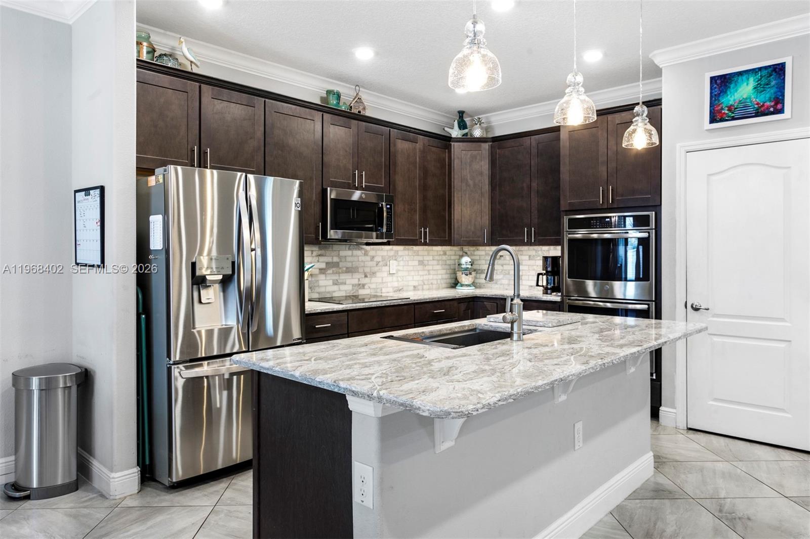 1773 Southwest Palermo Road Port St. Lucie, FL 34987 - Photo 11 of 50 Chef's quality kitchen with Quartz top island, marble backsplash with undermount lighting, wood cabinetry, SS appliances, double oven, and pantry.